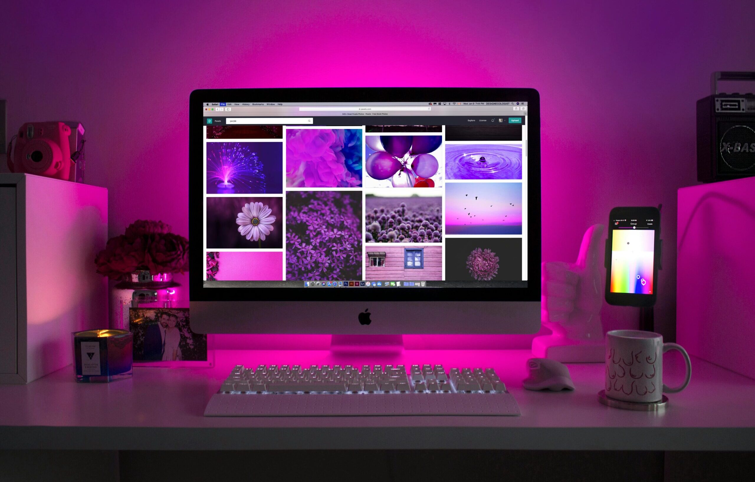 Modern desk setup with neon lighting and a desktop computer displaying colorful images.